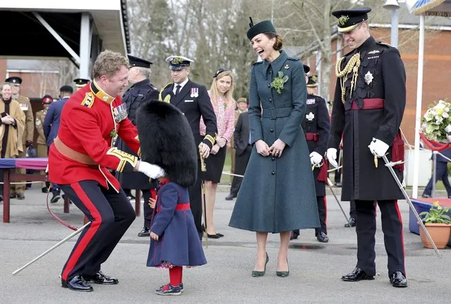 Britain's Kate, Duchess of Cambridge and Prince William laugh as Lieutenant Colonel Rob Money puts a bearskin hat on his 20-month-old daughter Gaia Money's head as they attend the 1st Battalion Irish Guards' St. Patrick's Day Parade at Mons Barracks, Thursday March 17, 2022 in Aldershot, England. (Photo by Chris Jackson, Pool via AP Photo)