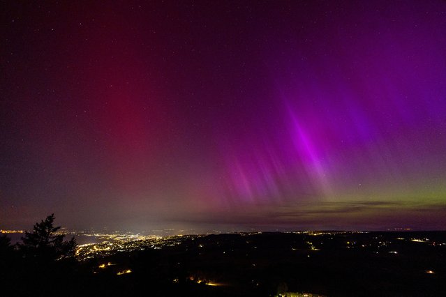 An aurora borealis is seen above Lausanne and the Jura from the Tour de Gourze in Riex, Switzerland, on May 11, 2024. (Photo by Denis Balibouse/Reuters)