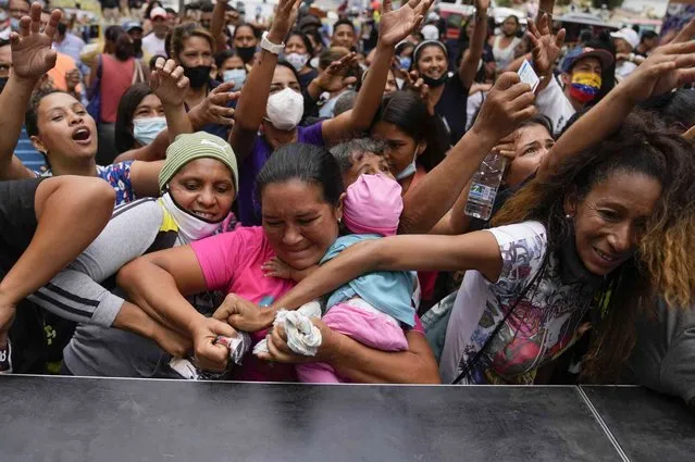 Demonstrators fight for free t-shirts during a demonstration to demand de release of Colombian businessman Alex Saab who has been extradited to the U.S., during a protest in the Petare neighborhood of Caracas, Venezuela, Monday, April 4, 2022. Saab, a close ally of Venezuela's President Nicolas Maduro, who prosecutors in the U.S. believe could be the most significant witness ever about corruption in the South American country, was extradited from Cabo Verde and is now in U.S. custody. (Photo by Ariana Cubillos/AP Photo)