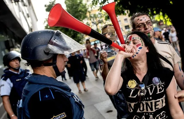 Protesters blow vuvuzelas in front of police officers during an anti-government protest dubbed the “Colorful Revolution”, in Skopje, The Former Yogoslav Republic of Macedonia, 30 May 2016. The political crisis in Macedonia postponed elections due for next month, after the European Union called on Skopje to delay the polls to ensure they could take place freely and fairly. The delay was agreed by parliament, which reconvened after Macedonian constitutional court froze all activities related to the controversial parliamentary election scheduled for 05 July this year. (Photo by Georgi Licovski/EPA)