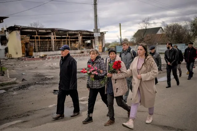 Tetyana Boikiv, 52, center, walks with family members and neighbours during a funeral service for her husband, Mykola Moroz, 47, at the Ozera village, near Bucha, Ukraine on Tuesday, April 26, 2022. Mykola was captured by Russian army from his house in the Ozera village on March 13, taken for several weeks in an unknown location and finally found killed with gunshots about 15 kilometres from his house. (Photo by Emilio Morenatti/AP Photo)
