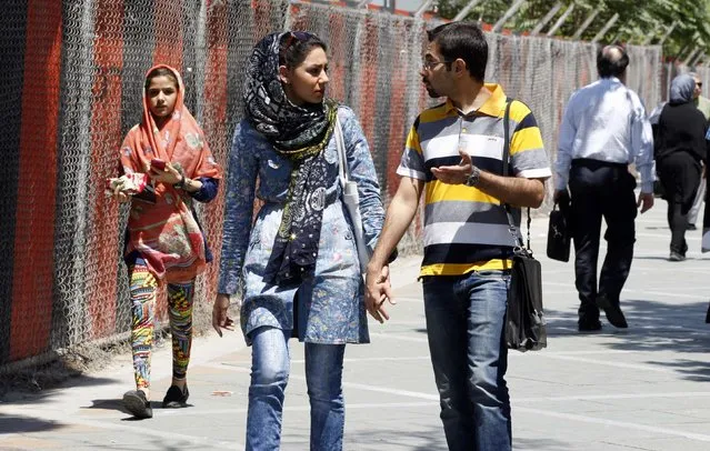 A couple walk on a sidewalk  in northern Tehran, Iran, July 27, 2015. (Photo by Reuters/TIMA)