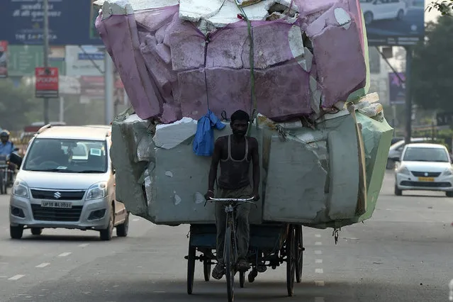 This photo taken on October 3, 2019, shows a labourer transporting a large load of non bio-degradable thermocol and styrofoam waste sheets on a road on the outskirts of New Delhi. (Photo by Prakash Singh/AFP Photo)
