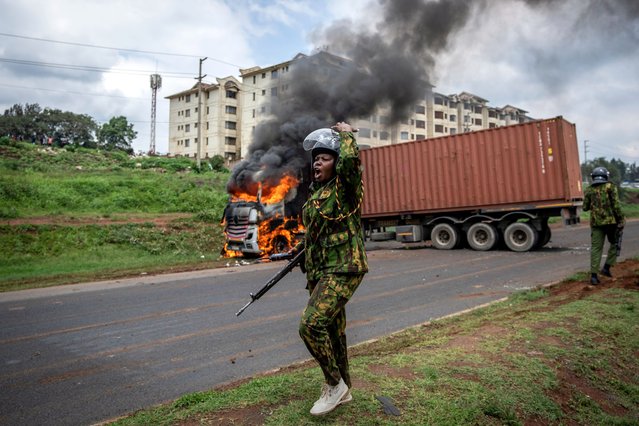 A riot policewoman calls for reinforcements to come after opposition protesters set fire to a truck after failing to open the container it was transporting, during clashes in the Kibera slum of the capital Nairobi, Kenya Tuesday, May 2, 2023. The fresh round of demonstrations called by opposition leader Raila Odinga demanded action to tackle the cost of living and reforms to the electoral commission that oversaw last year's election that was won by President William Ruto. (Photo by Ben Curtis/AP Photo)