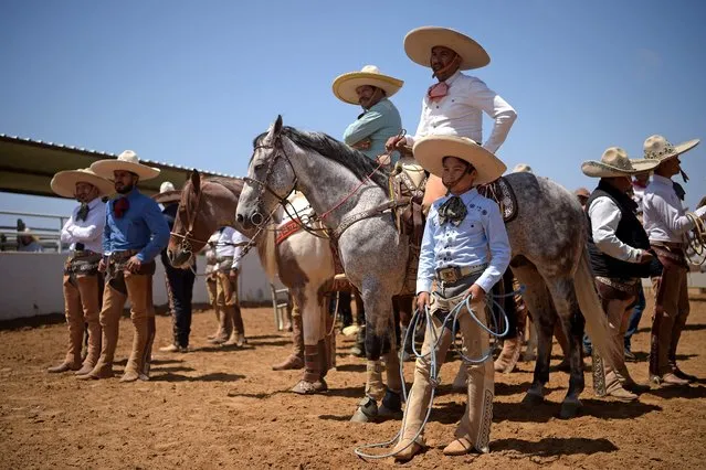 Men wearing traditional charro attire attend a charreria competition at Rancho La Laguna in San Ysidro, south of San Diego near the US-Mexico border, California on May 8, 2022. A charro is a Mexican horseman or cowboy, typically one wearing an elaborate outfit, often with silver decorations, of tight trousers, ruffled shirt, short jacket, and sombrero. The traditional charro competition charreada or charreria (similar to a rodeo) has become the official sport of Mexico and maintains traditional rules and regulations in effect from colonial times up to the Mexican Revolution. (Photo by Agustin Paullier/AFP Photo)