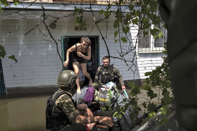 Local resident Olena gets on a small boat as she is evacuated by Ukrainian servicemen from a flooded neighborhood in Kherson, Ukraine, Thursday, June 8, 2023. Many small boats carrying volunteers and Ukrainian soldiers have shuttled across from Ukrainian-held areas on the west bank to rescue desperate civilians stuck on rooftops, in attics and in other areas amid the deluge. (Photo by Evgeniy Maloletka/AP Photo)