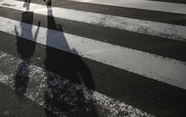 A mother and daughter cast shadows on a street crossing in Nagasaki, southwestern Japan, July 31, 2015. (Photo by Issei Kato/Reuters)