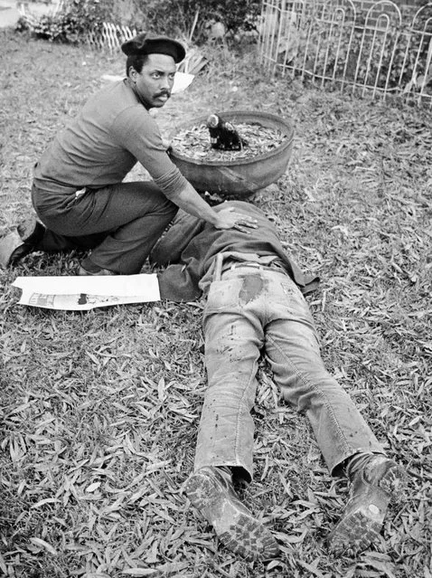 In this November 3, 1979 file photo, Workers Viewpoint Organization member Nelson Johnson kneels by victim in aftermath of shooting in Greensboro, N.C.  The state, with the blessing of the Greensboro City Council, will use the word “massacre” for a highway historical marker commemorating the deaths of five Communist Workers Party members during a confrontation with Ku Klux Klansmen and the American Nazi Party. (Photo by Jim Stratford /News & Record via AP Photo)