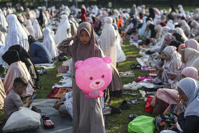 A girl holds a balloon as Indonesian Muslims attend the Eid al-Adha prayer on the football field in Depok, West Java, Indonesia, on June 28, 2023. (Photo by Agoes Rudianto/Anadolu Agency)