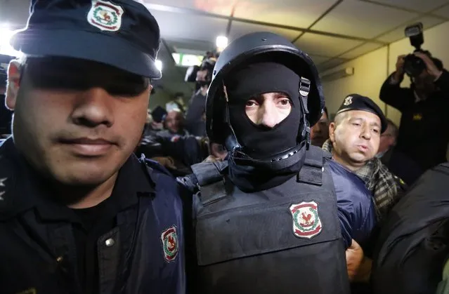 Ibar Esteban Perez Corradi, center, is escorted by police officers to a court hearing, in Asuncion, Paraguay, Tuesday, June 21, 2016. After several years on the run, the Argentine fugitive was arrested in Paraguay on Sunday. He is suspected as the mastermind of a 2008 triple murder related to trafficking ephedrine. Argentina has launched the process for his extradition to face the murder accusations. (Photo by Jorge Saenz/AP Photo)
