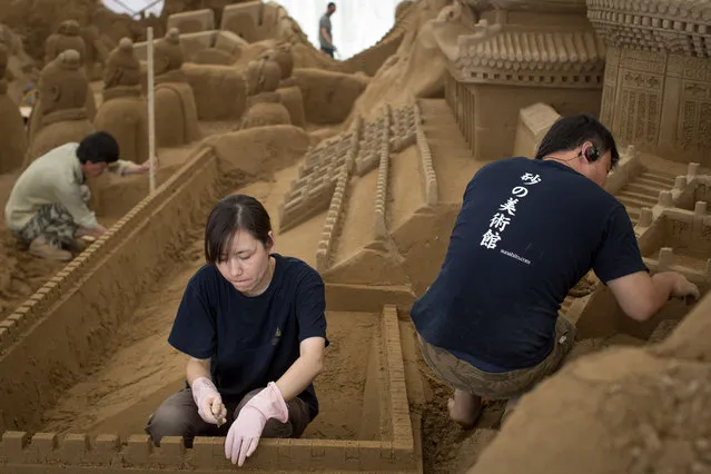 Sand sculptors Zhang Weikang, (L) Zhang Yan, (C) and Yang Lidong of China work to finish the Chinese section of a large sand sculpture at the site of Yokohama Sand Art Exhibition – Culture City of East Asia 2014 on July 16, 2014 in Yokohama, Japan. Producer and sand sculptor Katsuhiko Chaen invited artists from around the world including South Korea and China, to recreate the World Heritage and historical buildings in China, Japan and South Korea. The exhibition will be open from July 19 to November 3, 2014. (Photo by Chris McGrath/Getty Images)