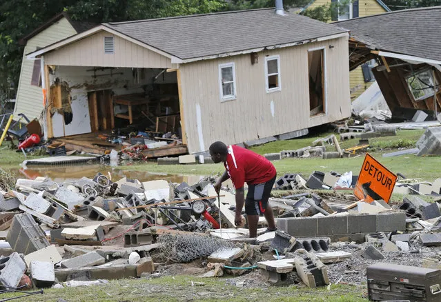 A White Sulphur Springs resident sorts through debris as the cleanup begins from severe flooding in White Sulphur Springs, W. Va., Friday, June 24, 2016. (Photo by Steve Helber/AP Photo)