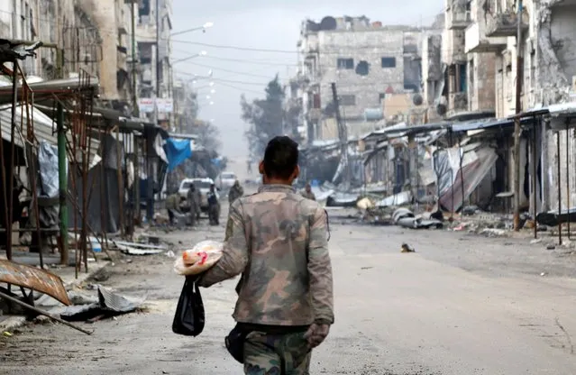 A Syrian army soldier carries food as he walks through Maarat al-Numan, Syria, January 30, 2020. Backed by Russian air power, government forces have rapidly advanced on Idlib since last week, upending an area where millions have taken refuge. (Photo by Omar Sanadiki/Reuters)