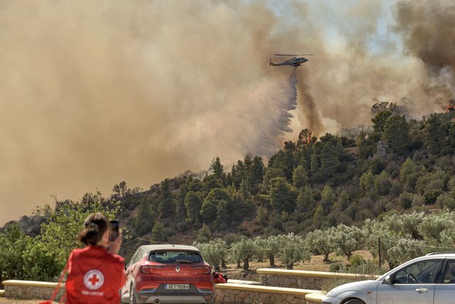 A fire-fighting helicopter drops water over a wild fire near Prodromos, 100km northeast from Athens, on August 21, 2023. (Photo by Spyros Bakalis/AFP Photo)