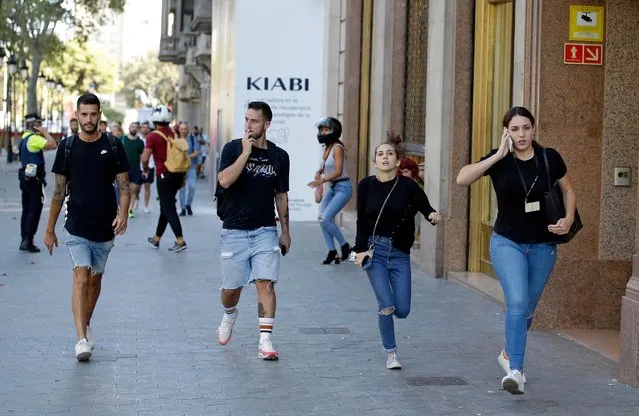 People run down a street in Barcelona, Spain, Thursday, August 17, 2017. Police in the northern Spanish city of Barcelona say a white van has jumped the sidewalk in the city's historic Las Ramblas district, injuring several people. (Photo by Manu Fernandez/AP Photo)
