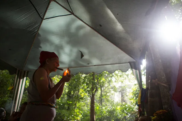 A woman lights a cigar at a camp at the Sorte Mountain on the outskirts of Chivacoa, in the state of Yaracuy, Venezuela October 10, 2015. (Photo by Marco Bello/Reuters)