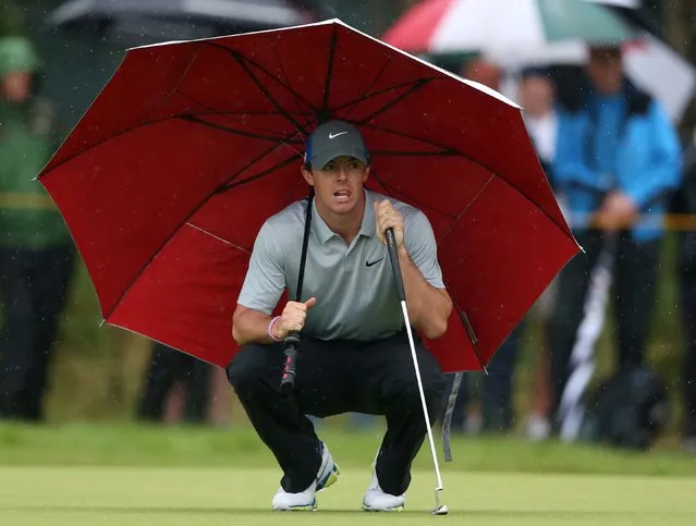 Rory McIlroy kneels under an umbrella as he waits to play on the 4th green during the third day of the British Open at the Royal Liverpool golf club in Hoylake, England, on Jule 19, 2014. McIlroy  finished the round with a six stroke lead. (Photo by Jon Super/Associated Press)