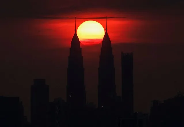 The sun sets behind the Petronas Twin Towers, in Kuala Lumpur, Malaysia, June 7, 2022. (Photo by Hasnoor Hussain/Reuters)
