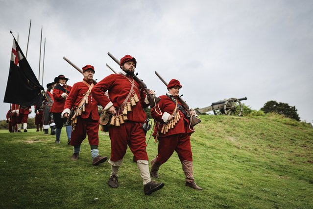 Members of The Marquis of Winchester Regiment march from the battlefield following a battle while taking part in a re-enactment of the 1645 English Civil War, at Old Basing House near Basingstoke south east England, on September 17, 2023. After the decisive defeat of King Charles I's army at Naseby in Northamptonshire in June 1645 Oliver Cromwell led part of the New Model Army to "mop up" remaining royalist bases in Wiltshire and Hampshire. He appeared before Basing House around 8 October, determined to capture this major royalist stronghold, containing both a garrison and civilians, including many Catholics, which had resisted earlier sieges and had long been a thorn in parliament's side. He subjected the place to heavy bombardment and by the 13 had opened up breaches in the defences. He and his men stormed and captured the stronghold on the morning of 14 October. (Photo by Adrian Dennis/AFP Photo)