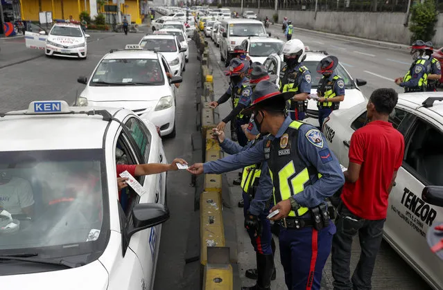A taxi driver shows his ID and car documents to police who instructed them to stop operations while the government implements the “enhanced community quarantine” as a precautionary measure against the spread of the new coronavirus in Manila, Philippines, early Tuesday, March 17, 2020. (Photo by Aaron Favila/AP Photo)