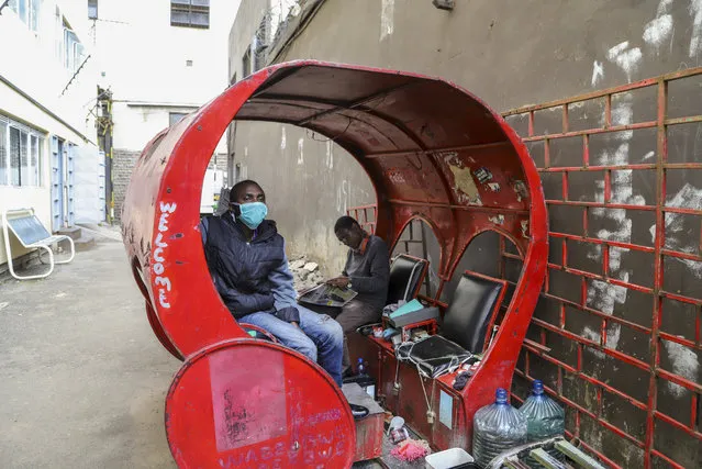 Francis Kimani Waweru sits in his shoeshine stall, which he complains has seen few customers since fears of the new coronavirus took hold, on a street in downtown Nairobi, Kenya Friday, March 20, 2020. (Photo by Patrick Ngugi/AP Photo)
