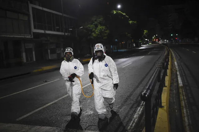 City workers walk after spraying disinfectant on the streets as a preventive measure against the spread of the new coronavirus, in Caracas, Venezuela, Saturday, March 21, 2020. (Photo by Matias Delacroix/AP Photo)