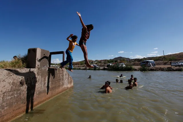 Girls jump into the Rio Bravo to cool off during a hot summer day on the Mexican side of the river near the fence marking the border between Mexico and the U.S in Ciudad Juarez, Mexico, July 24, 2016. (Photo by Jose Luis Gonzalez/Reuters)