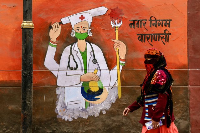 A woman with face covered in cloth, walks past a wall mural promoting awareness on using face masks, in Varanasi on January 7, 2025, amid alleged media reports suggesting that the Indian Council of Medical Research (ICMR) has detected cases of Human Metapneumovirus (HMPV) in India. (Photo by Niharika Kulkarni/AFP Photo)