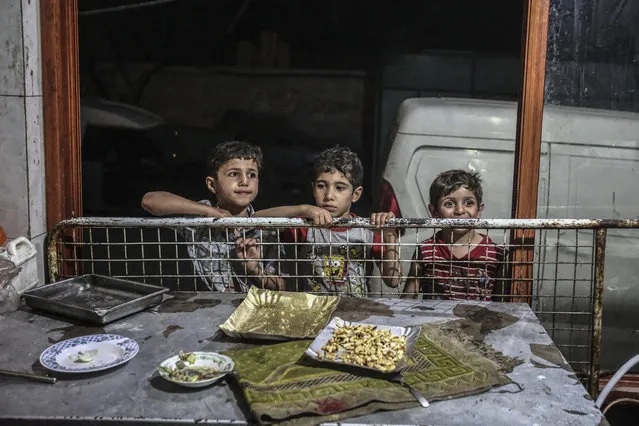 Syrian boys watch a vendor working at an ice cream parlor in Hamorya, Eastern al-Ghouta province, Syria, late 23 June 2016. Muslims around the world celebrate the holy month of Ramadan by praying during the night time and abstaining from eating and drinking during the period between sunrise and sunset. Ramadan is the ninth month in the Islamic calendar and it is believed that the Koran's first verse was revealed during its last 10 nights. (Photo by Mohammed Badra/EPA)