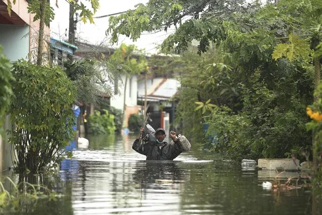 A resident wades through floodwaters, Thursday, September 29, 2022, in Ubon Ratchathani province, northeastern Thailand. Heavy rains and strong winds from tropical storm Noru swept across parts of northeastern Thailand on Thursday morning, knocking down trees and triggering flash floods in several areas. (Photo by Nava Sangthong/AP Photo)