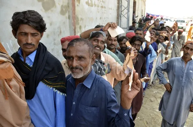 Displaced families, who fled their flood-hit homes, line up to get relief aid in Jaffarabad, a district of Baluchistan province, Pakistan, Wednesday, September 21, 2022. Devastating floods in Pakistan's worst-hit province have killed 10 more people in the past day, including four children, officials said Wednesday as the U.N. children's agency renewed its appeal for $39 million to help the most vulnerable flood victims. (Photo by Zahid Hussain/AP Photo)