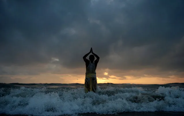 An Indian Hindu devotee pray to the Sun god standing on shores of Bay of Bengal at marina beach during Chhath Puja festival in Chennai on October 27, 2017. During Chhath, an ancient Hindu festival, rituals are performed to thank the Sun god for sustaining life on earth. The Chhath Festival, also known as Surya Pooja, or worship of the sun, is observed in parts of India and Nepal and sees devotees pay homage to the sun and water gods. Devotees undergo a fast and offer water and milk to the sun god at dawn and dusk on the banks of rivers or small ponds and pray for the longivety and health of their spouse. (Photo by Arun Sankar/AFP Photo)