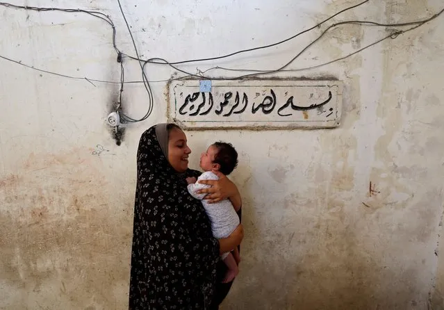 Lamis Kuhail, 12, plays with her 2 month old brother, Ahmed, at their family home in the Sheikh Shaban cemetery, Gaza City, August 27, 2022. (Photo by Mohammed Salem/Reuters)