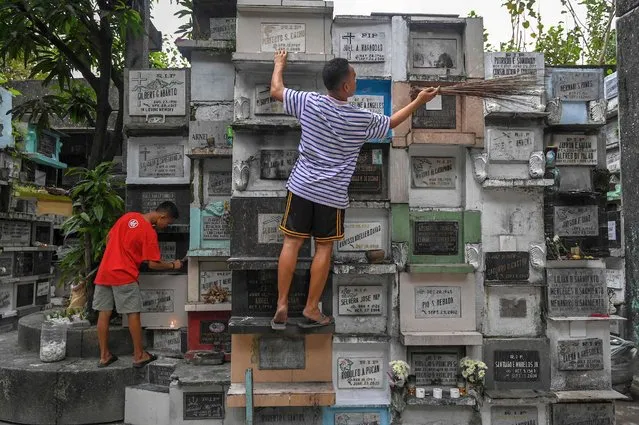 Men clean a cemetery in Manila on October 25, 2022, ahead of All Saints’ Day on November 1. (Photo by Jam Sta Rosa/AFP Photo)