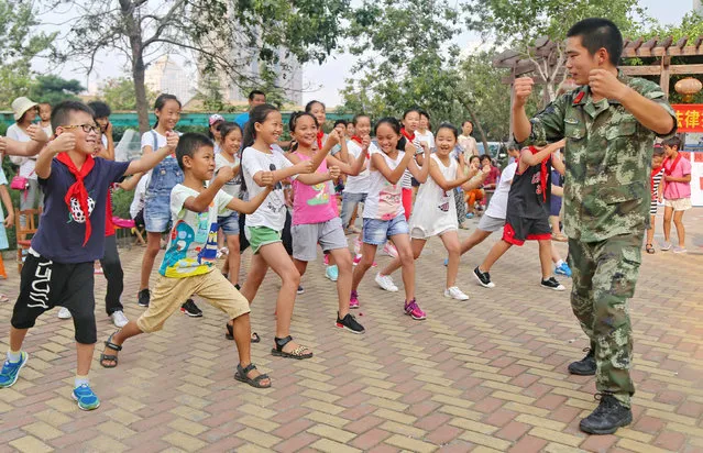 A paramilitary policeman teaches children self-defense techniques in Qinhuangdao, Hebei province, China, August 24, 2016. (Photo by Reuters/China Daily)