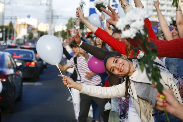 People wave flowers as they gather to protest against the results of the country's presidential election in Minsk, Belarus, Thursday, August 13, 2020. Crowds of protesters in Belarus swarmed the streets and thousands of workers rallied outside industrial plants to denounce a police crackdown on demonstrations over a disputed election that extended the 26-year rule of authoritarian President Alexander Lukashenko. (Photo by Sergei Grits/AP Photo)