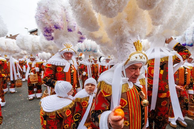 Participants costumed as Gilles of Binche wear hats with plumes of ostrich feathers during the carnival parade in Binche, Belgium, 13 February 2024. On average, 250 to 300 feathers are needed to make the 1.5 meters high 8 to 9 large plumes. The Gilles throw oranges as a gift of good luck. It is an insult to throw them back. Having earned UNESCO's recognition as a Masterpiece of the Oral and Intangible Heritage of Humanity, the Carnival of Binche is in discussion with the organisation to explore ways to make the tradition more inclusive, while respecting the long-standing rules that currently restrict participation to male performers. (Photo by Olivier Matthys/EPA)