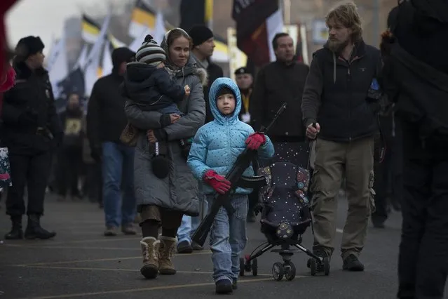 A boy holds a toy rifle during a Russian nationalist march in support of pro-Russian separatists fighting with Ukrainian government forces in eastern Ukraine in Moscow to mark People's Unity Day, a public holiday in Russia, on Tuesday November 4, 2014. (Photo by Alexander Zemlianichenko/AP Photo)