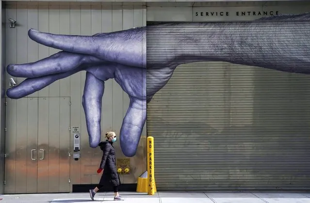 The Pandemic. A woman in a mask walks past a mural of a hand on the side of a building in New York. The photo was taken on 22 April, during the citywide coronavirus lockdown. (Photo by Timothy A Clary/AFP Photo/International Festival of Photojournalism 2020)