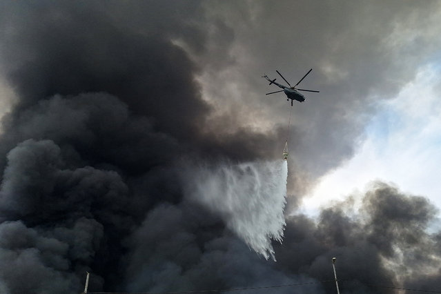 A helicopter sprays water at the scene of an explosion that took place a day earlier at the Shahid Rajaee port dock, southwest of Bandar Abbas in the Iranian province of Hormozgan, on April 27, 2025. Fire blazed on April 27, around 24 hours after a massive explosion tore through Iran's largest commercial port, killing at least 28 people and leaving more than 1,000 others injured, according to the Red Crescent. (Photo by Meysam Mirsadeh/Tasnim News via AFP Photo)