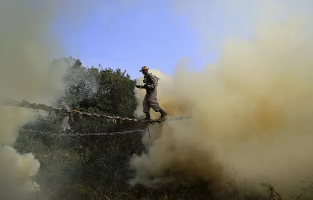 Indian army soldiers cross a rope bridge amid smoke from canisters as they showcase skills during a training session at the army's Madras Engineer Group training centre in Bangalore, India, Wednesday, January 17, 2018. (Photo by Aijaz Rahi/AP Photo)