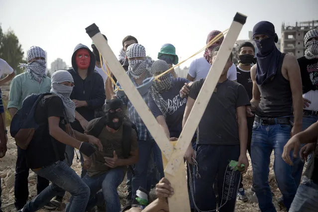 Palestinians uses a handmade large slingshot to hurl a stone during clashes with Israeli troops near Ramallah, West Bank, Monday, October 12, 2015. Recent days have seen a series of stabbing attacks in Israel and the West Bank that have wounded several Israelis. Past weeks have also seen violent demonstrations in the West Bank and Gaza, and at least 16 Palestinians have been killed by Israeli forces. (Photo by Majdi Mohammed/AP Photo)