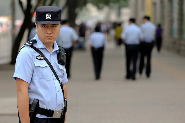 A policeman keeps an eye on reporters as he secures the area near the Beijing Number 2 People's Intermediate Court where the sentencing for civil rights lawyer Xia Lin takes place in Beijing, China September 22, 2016. (Photo by Damir Sagolj/Reuters)