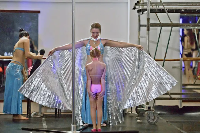 In this September 10, 2016 picture, Diana Romaniuc, 7 years-old, reacts upon seeing the shiny outfit of a belly dancer before competing in the children category of the Romania Miss Pole Dance Contest, ahead of the finals of the Pole Sport&Fitness World Championship 2016 in Bucharest, Romania. (Photo by Vadim Ghirda/AP Photo)