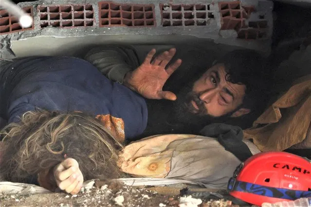 Abdulalim Muaini lies under the rubble next to the body of his wife Esra, in the aftermath of a deadly earthquake in Hatay, Turkey on February 8, 2023. (Photo by Umit Bektas/Reuters)