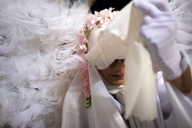 A young woman dressed as an angel adjusts her burqa as she rests after performing in a ceremony to commemorate women and children killed in the 12-day war between Iran and Israel, at the Imam Khomeini Grand Mosque in Tehran, Iran, on July 30, 2025. Iranian officials say that 110 children and women are killed during Israeli attacks on residential and civilian areas in Iran. (Photo by Morteza Nikoubazl/NurPhoto/Rex Features/Shutterstock)