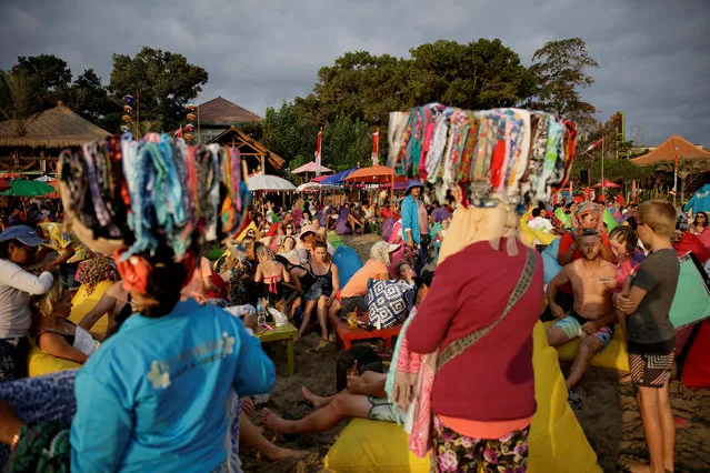 Vendors sell bandanas as tourists watch the sunset on Seminyak beach in Bali, Indonesia August 17, 2017. (Photo by Thomas White/Reuters)