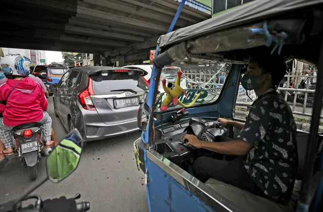 A man waits with his three-wheeled motorized taxi called the “bajaj” in a traffic jam in Jakarta, Indonesia, Thursday, November 5, 2020. (Photo by Dita Alangkara/AP Photo)