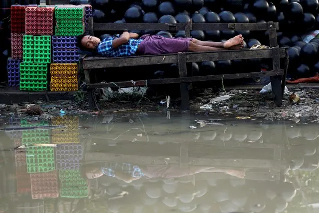 A man sleeps on a bench along a flooded street in Yangon in this September 30, 2015 file photo. (Photo by Soe Zeya Tun/Reuters)