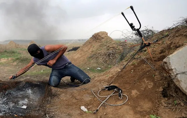 A Palestinian protester uses sling shot to hurl stones at Israeli troops during clashes near border between Israel and Central Gaza Strip November 6, 2015. (Photo by Ibraheem Abu Mustafa/Reuters)